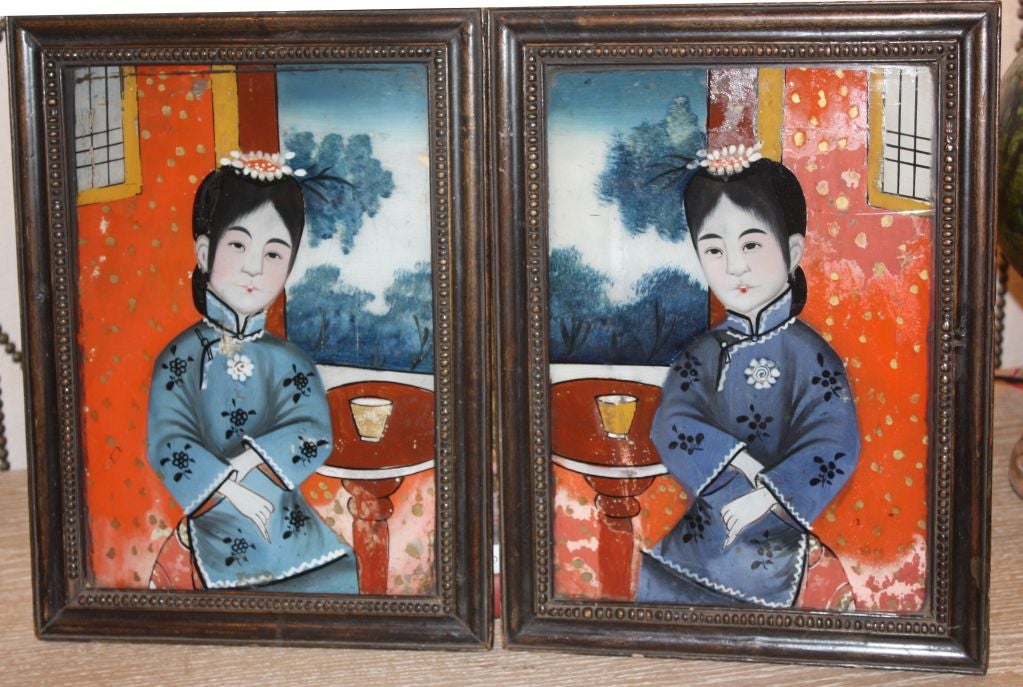 A charming pair of Chinese eglomise portraits(reverse paintings on glass) of young girls seated at a table having tea, the glass panels are without cracks and are in their original carved wood frames, circa 1870.