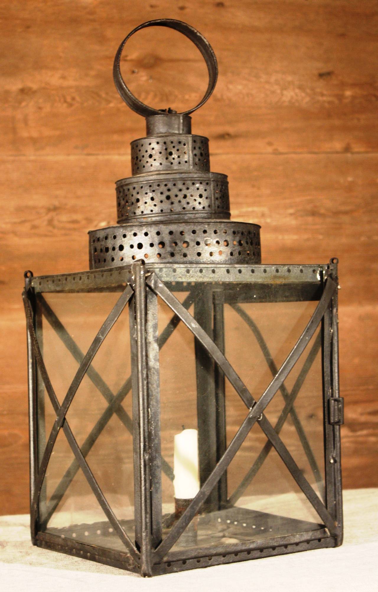 A primitive pierced tin and glass lantern with a single candle holder, American 19th century.