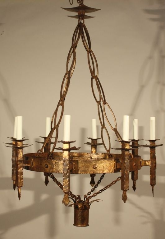 An interesting Gothic inspired gilt-iron chandelier, French mid 1930's with 8 electrified candles and a light in the drop pendant.