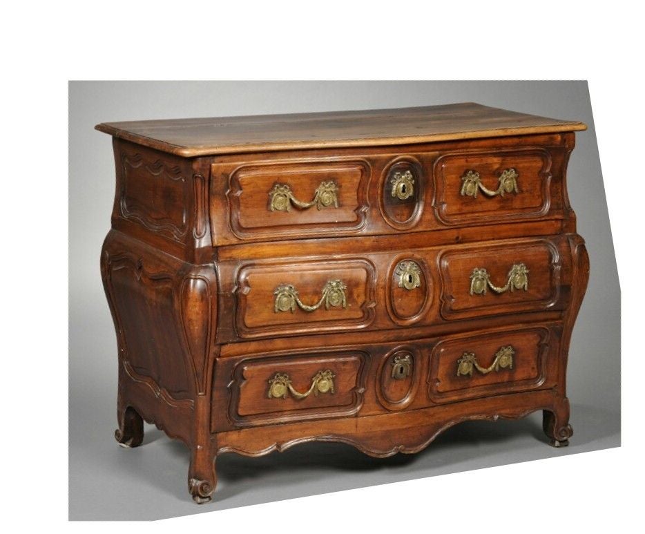 A fine and nicely proportioned French provincial Bombe' commode in fruitwood, circa 1770 retaining its original serpenting wood top over three lon carved and molded drawers each with period brass drawer pulls and key escutcheons, a scalloped and