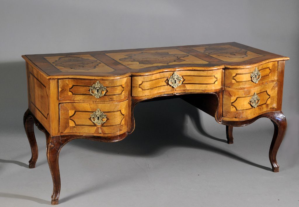 A very rare and exceptional Continental (German or Northern Italian) kneehole desk with abundant inlay on all sides, serpentine front and contrasting walnut cabriolle legs.