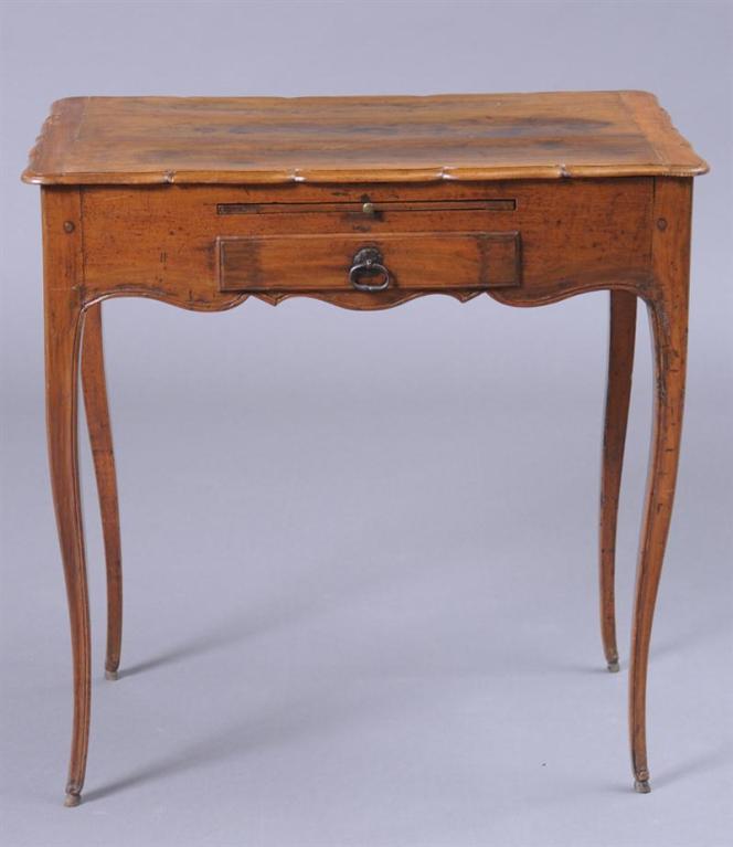 A French Louis XV poudreuse in walnut with slender cabriolle legs, a small drawer, and a scalloped apron and hinged top concealing a fabric lined storage area and mirror, circa 1760.