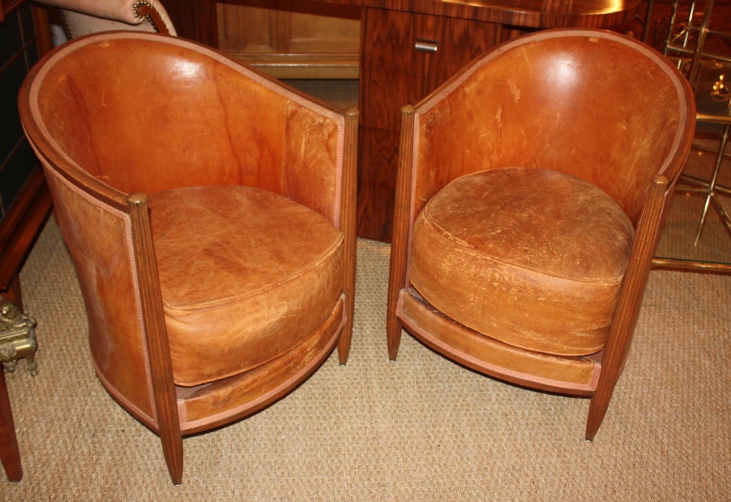 A good pair of small-scale leather club chairs, French Art-Deco period circa 1930, the oak barrel-back frames with fluted front legs in the manner of Ruhlmann.