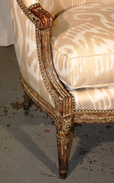 A fine Louis XVI Period bergere gondole with a nicely patinated frame retaining some of its original grey painted finish, currently upholstered in silk Ikat fabric, with a down filled loose cushion.