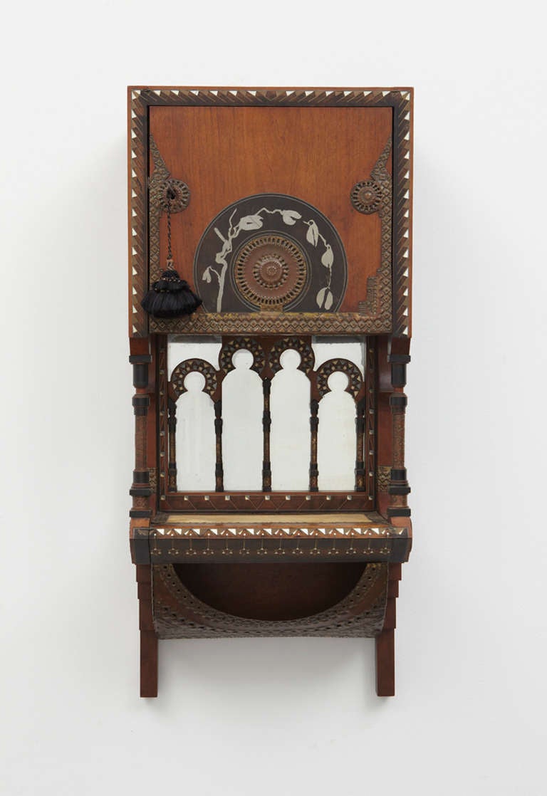 Wall-mounted hanging cabinet of walnut with mirrored back and inlays of bone, pewter, brass and fabric.

Excellent condition.