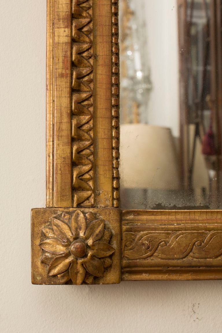 The rectangular mirror plate within a bead and reel border surmounted by musical instruments and foliage.