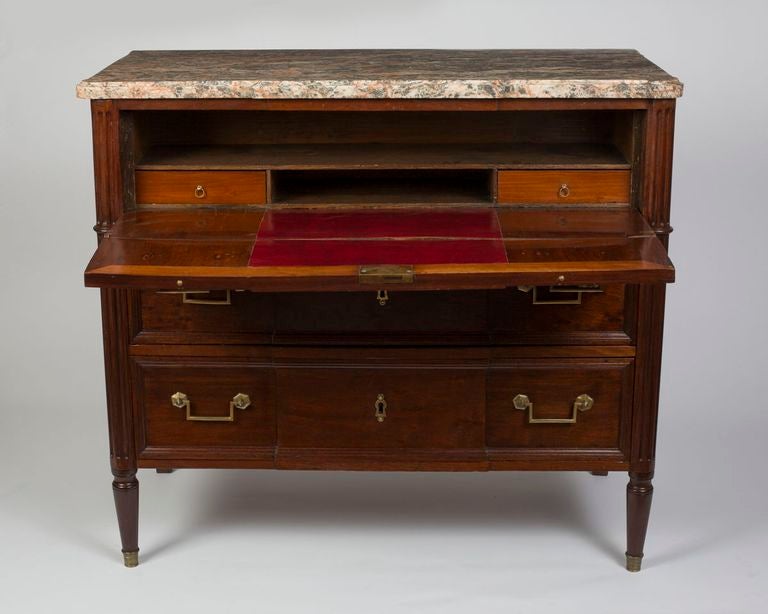The peche and gray veined marble top with rounded angles, above a long drawer enclosing a leather lined writing surface, an open compartment and two short drawers, above two long drawers, raised on turned tapering legs. 
Provenance: Baron Voruz de