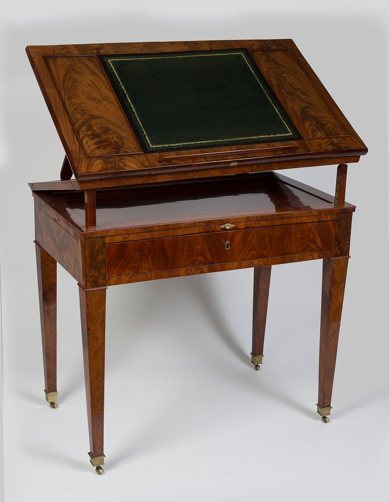 The double-ratchetted adjustable rectangular top with an ebony leather-lined writing slope with spring mechanism and with removable book stop, above a frieze drawer enclosing a writing-slide and writing compartment, with a writing-slide to each end,
