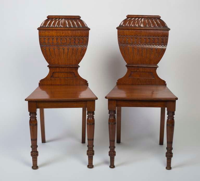 Each with a gadrooned and fluted urn-form splat, raised on circular tapering and ring-turned front legs and splayed back legs.