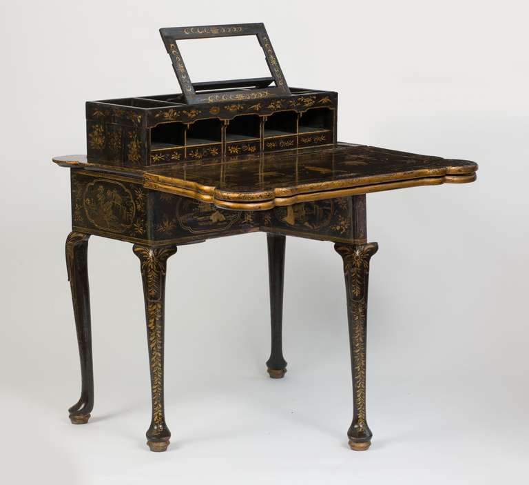 The triple-fold shaped hinged and eared top opening to a green baize-lined playing surface with money wells and candlestands first and a decorated writing surface second, the writing surface revealing a pop-up compartment with ratcheted book support