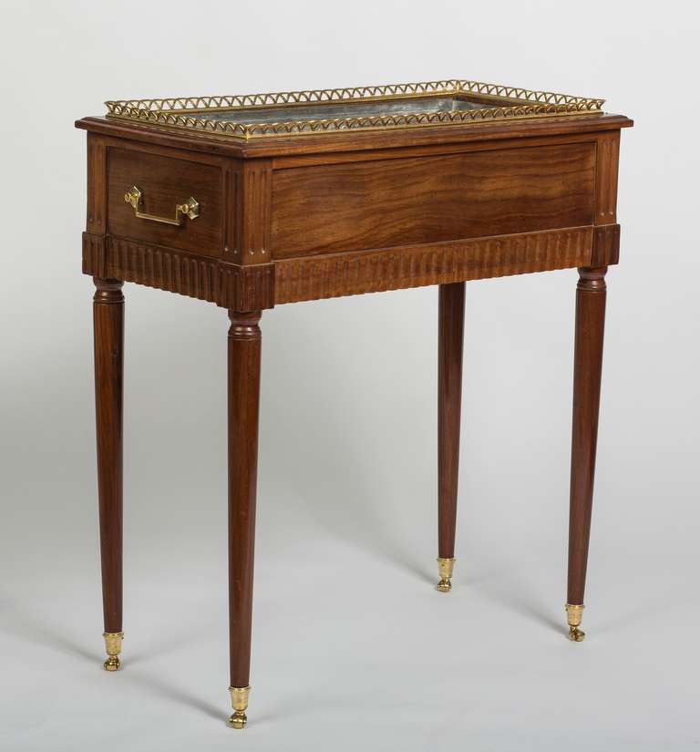 The rectangular moulded surround with a zinc liner with a pierced ormolu gallery, above a panelled frieze with a fluted edge, with later handles to the side, raised on turned tapering legs ending in ormolu caps and castors.
Joseph Gengenbach, known