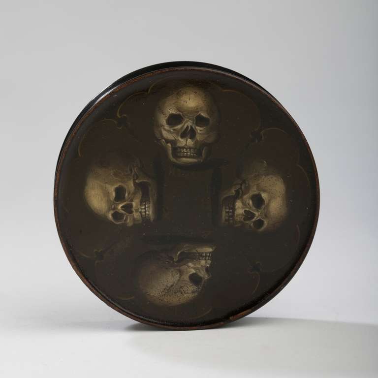 Decorado con cuatro calaveras en la parte superior con títulos de Bruja, Rey, Bella y Mendigo en cada calavera debajo. Con tapa.