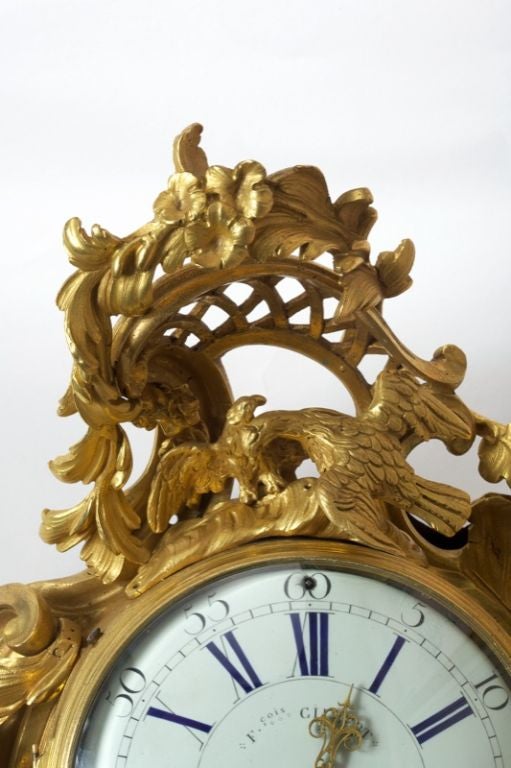 The circular enamelled dial with black Arabic and blue Roman numerals and the movement each signed 'F.cois GILBERT A PARIS' within an asymmetrical shaped case with C-scroll framing topped by two doves under a floral trellis, flanked by a foliate and