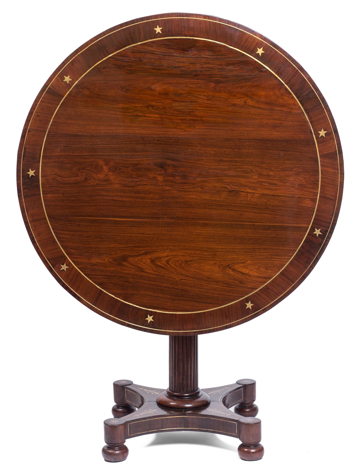 The circular tilt-top with inlaid brass stars above a fluted column raised on a brass inlaid quadripartite base, ending in bun feet.