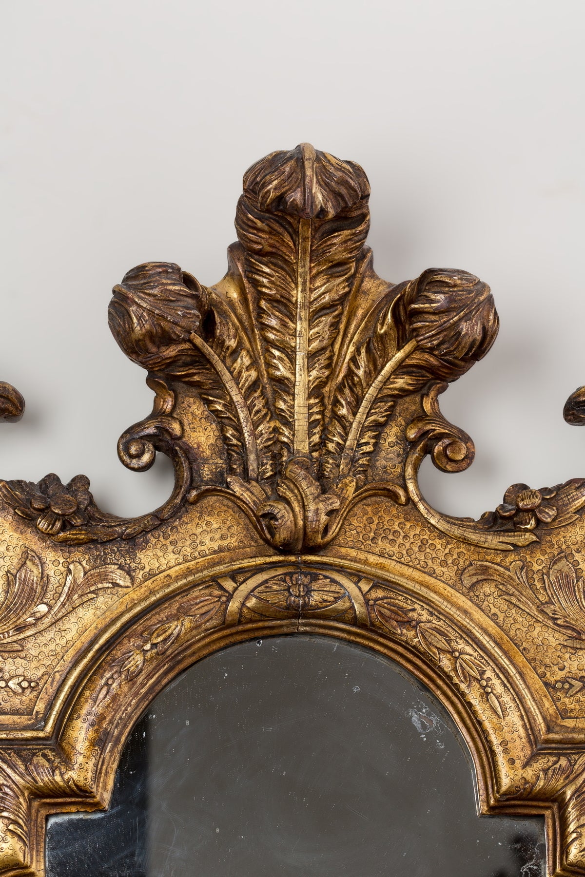 The shaped rectangular mirror plate within a carved and molded border, the voluted apron centered with a shell and scrolls on each side, the cresting with eagle heads flanking stylized plumes.