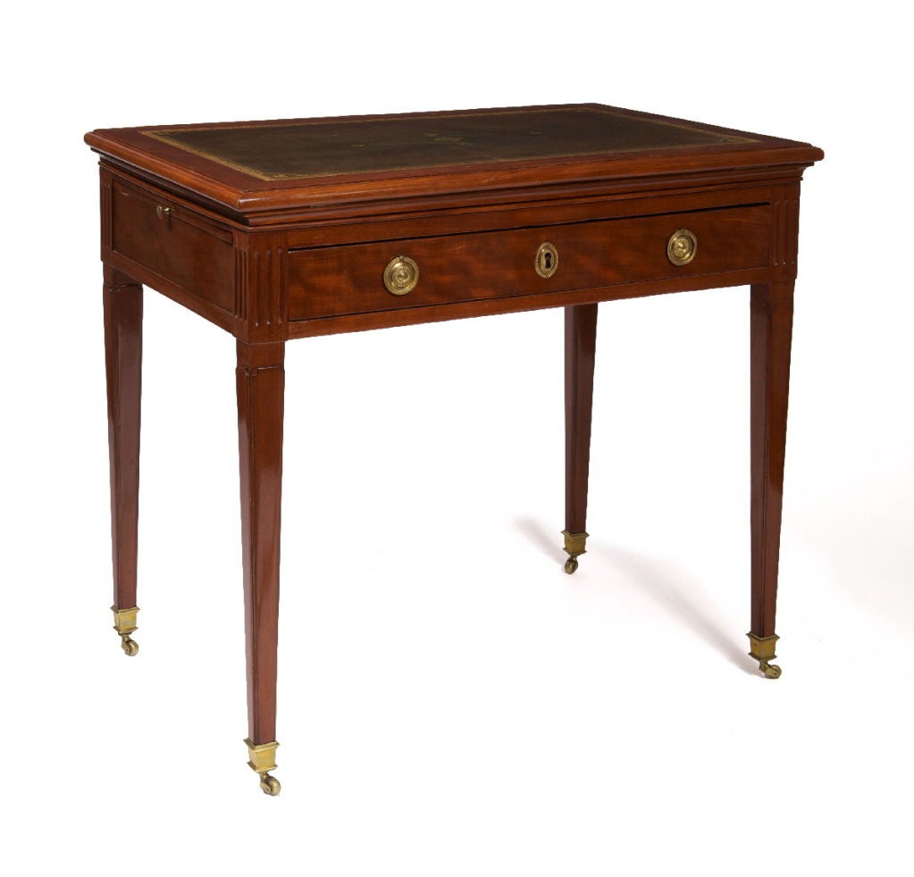 The double hinged ratcheted adjustable elevating top with a green tooled leather inset surface‚ above a frieze drawer enclosing a later writing slide, fitted with later slides to either side‚ on paneled square tapering legs headed by fluting and