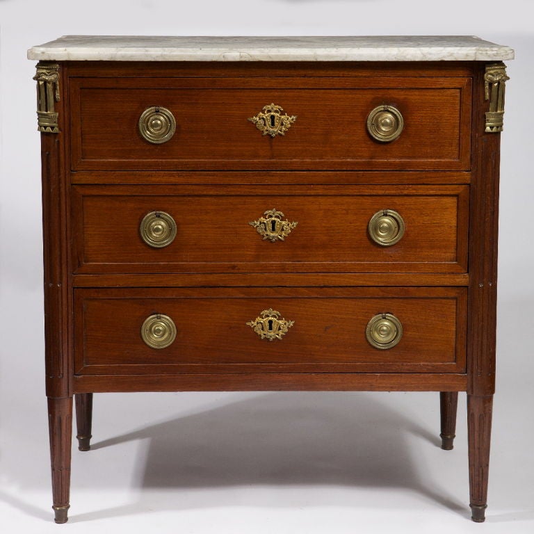 The original mottled white marble shaped top above three drawers flanked by stop-fluted columnar angles, raised on circular tapering stop-fluted legs ending in gilt-bronze sabots.