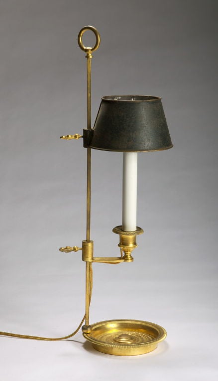 The candlestick with an adjustable candle arm and original tole shade above a fluted stem and a circular delicately chased gadrooned dish-shaped base. Fitted for electricity.