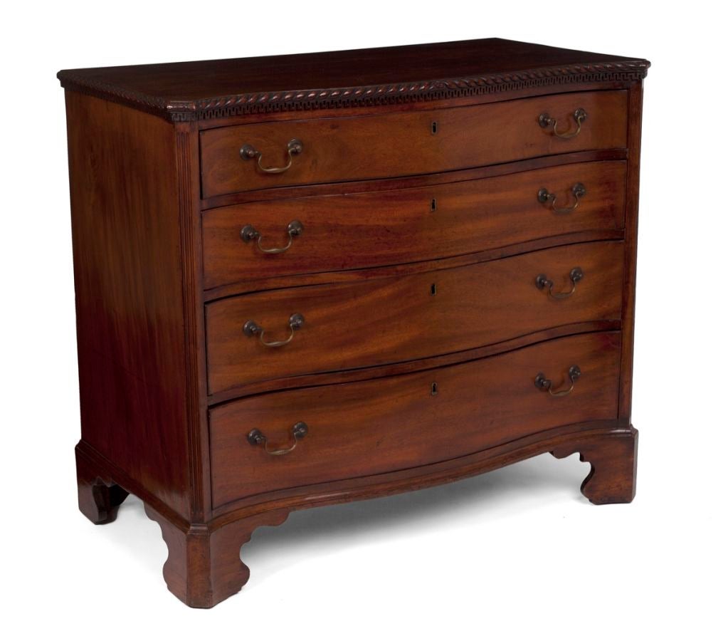 The top of serpentine outline with a rope twist border and a Greek key border underneath‚ above a conforming case enclosing four long graduated drawers between fluted carved angles‚ raised on elegantly shaped bracket feet.