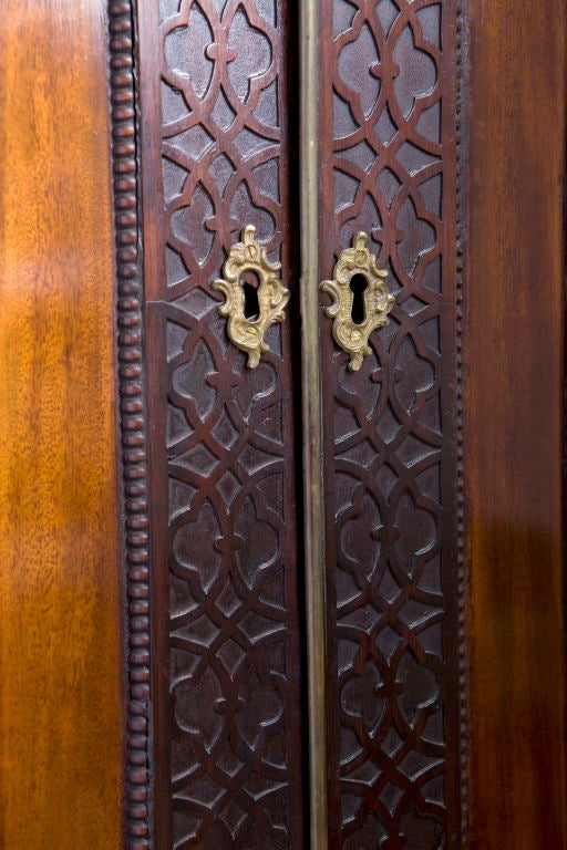 La cornice a traforo intagliata e traforata sovrasta una coppia di porte a pannelli con cornice a traforo cieca, l'interno è dotato di mensole e appendini (con una mensola), sopra due cassetti corti e due cassetti lunghi, sollevati su piedi a staffa