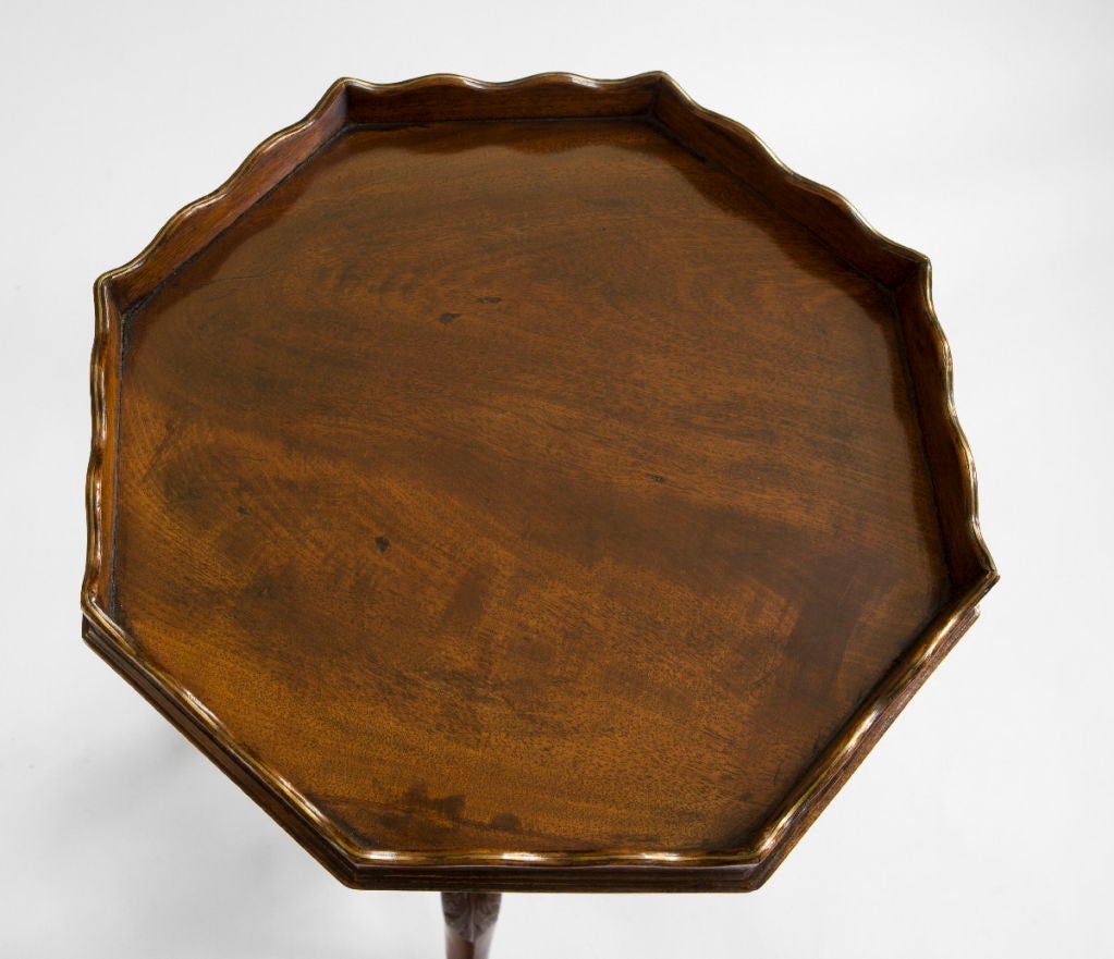 The associated octagonal top with a conforming gallery with an inlaid brass line‚ raised above a turned baluster with cabriole legs caved with scrolled foliage and ending in pointed pad feet.