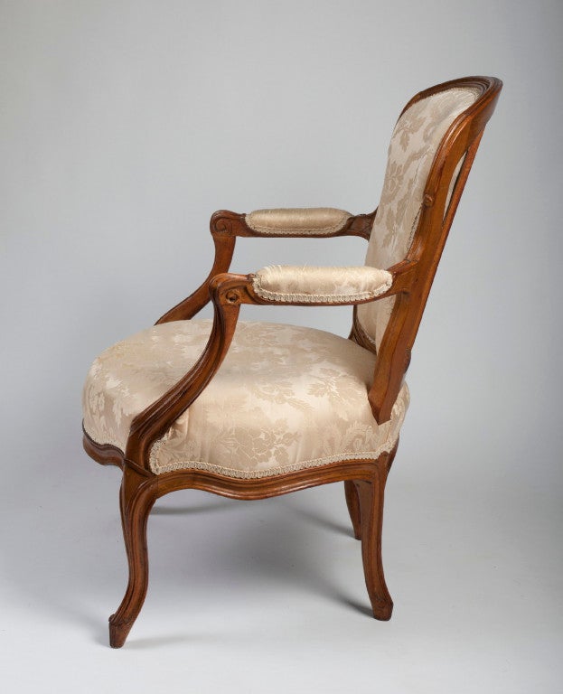 The arched molded crestrail above a padded back‚ armrests and a serpentine seat raised on molded cabriole legs. Stamped 