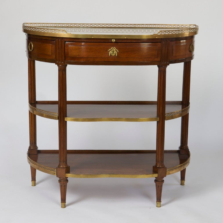 The shaped marble top within a three-quartered pierced gallery above a serving slide and a central molded frieze drawer and two curved swing-out side drawers, on fluted legs ending in fluted tapering feet, joined by two galleried shelves. 