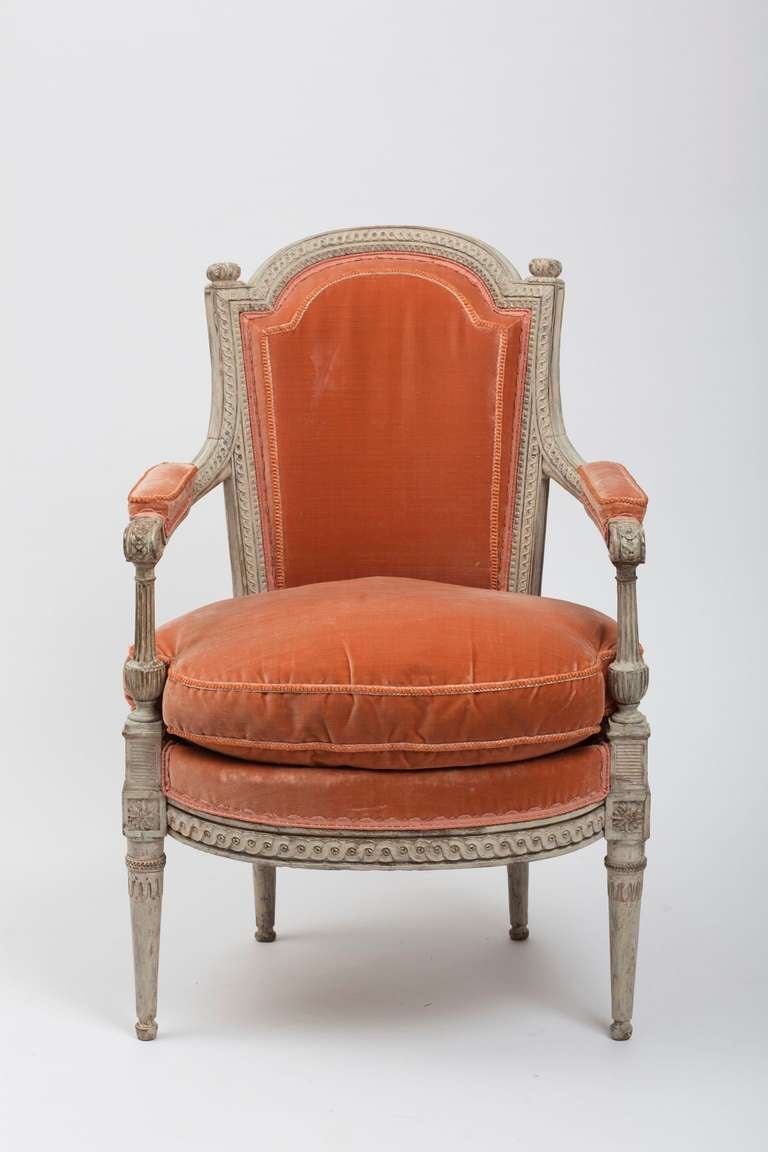 The arched crest rail with pomegranate-carved finials above a padded back and bow-fronted carved seat covered in orange silk velvet, within a guilloche frame flanked by baluster-shaped fluted arm supports, raised on tapering feet headed by paneled