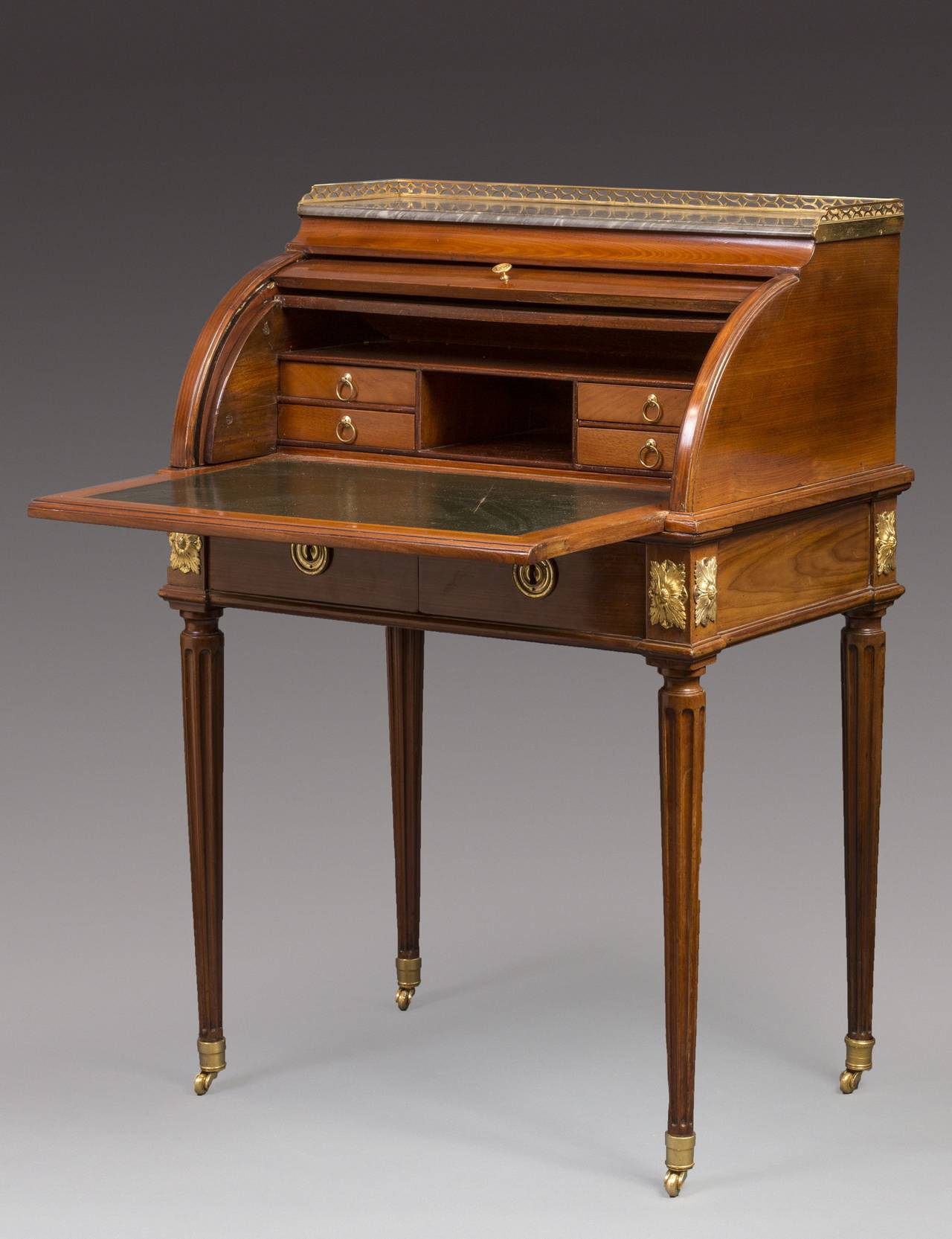 The recessed bleu turquin rectangular marble top with a three-quarter pierced gallery, above a cylinder rising to reveal a fitted interior with open compartments above and in between four drawers, with a pull-out sliding leather-lined writing
