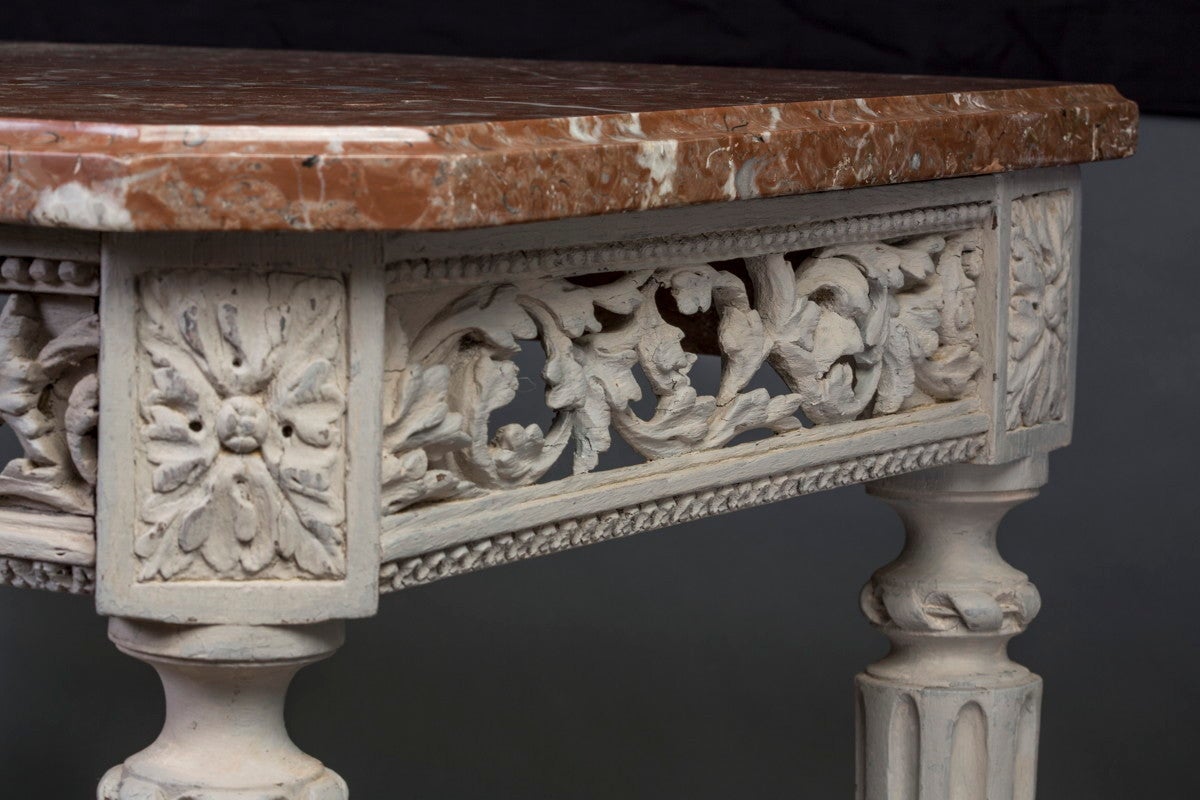 The red and white variegated molded rectangular original marble top with canted front corners above a pierced frieze finely carved with scrolling foliage, raised on four stop-fluted turned tapering legs headed by floral paterae and joined by a