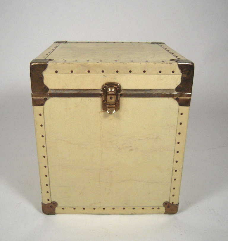 A buttery, cream colored,  textured, leather covered, brass bound square trunk.  Ideal as a side table, with added storage capability.