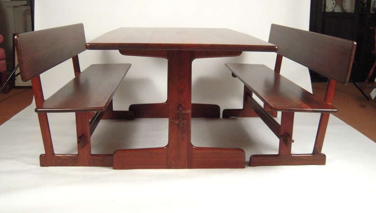 A fine quality Gerald McCabe (1928-2010) dining table, with a pair of matching benches in richly figured and colored shedua (African walnut)  wood, the swelled rectangular top supported by trestle supports and a stretcher joined with mortise and