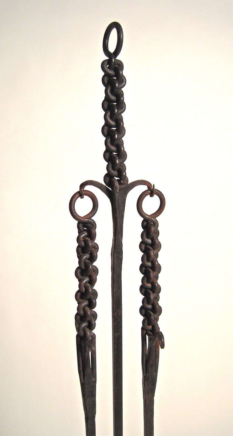An unusual wrought iron Arts and Crafts period fireplace tool set comprising a poker, shover and holder for the two, all with well made,  wrought iron chain-like decorative handles. Good, diminutive size for smaller sized fireplaces.