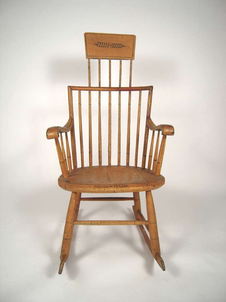 A 19th century American ochre yellow painted Windsor rocking chair, the headrest paint decorated with an 'M