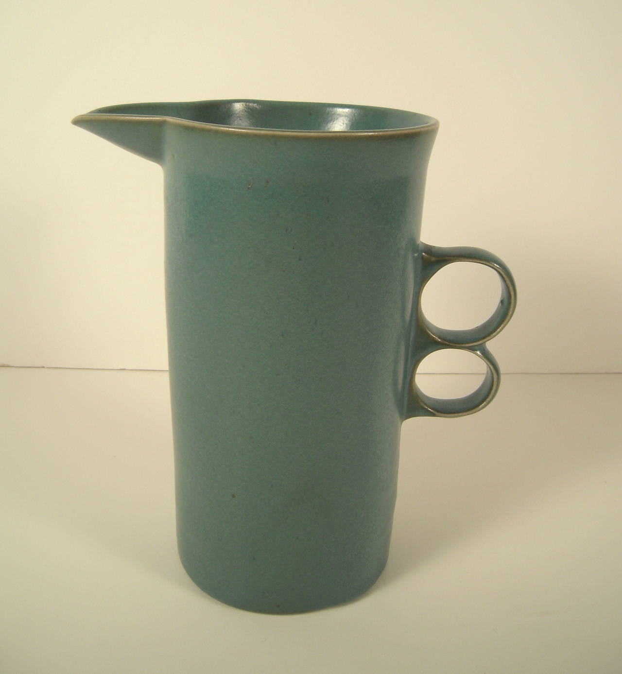 A vintage Bennington Potters stoneware pitcher glazed in teal, with trigger handle. Impressed maker's mark on bottom.