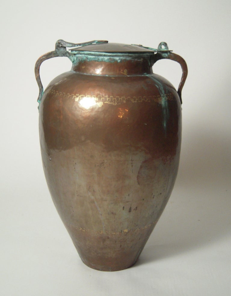 A large Persian hand made copper storage jar, the hinged cover flanked by two strap hinges attached to the tapering ovoid shaped vessel, hand made with dovetailed seams visible.

Acquired from a private collector who lived in Iran in the 1970s.