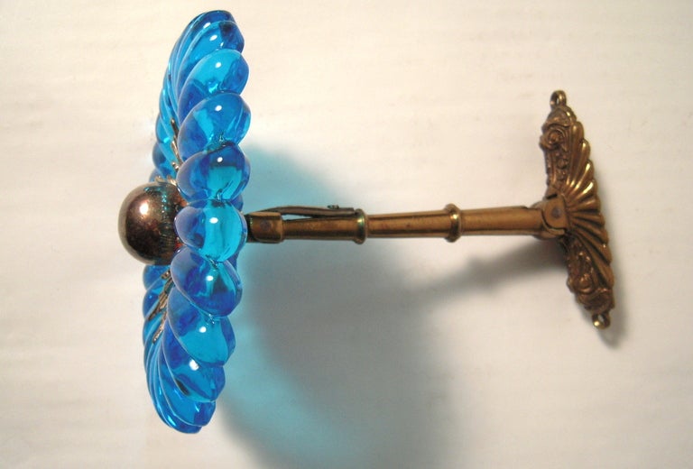 An exceptional set of 4 19th century luxurious, large light blue flower-form glass curtain tie backs, centered by silver plated orbs surrounded by sunbursts, attached to swiveling, adjustable brass rods terminating in neoclassical style oval back