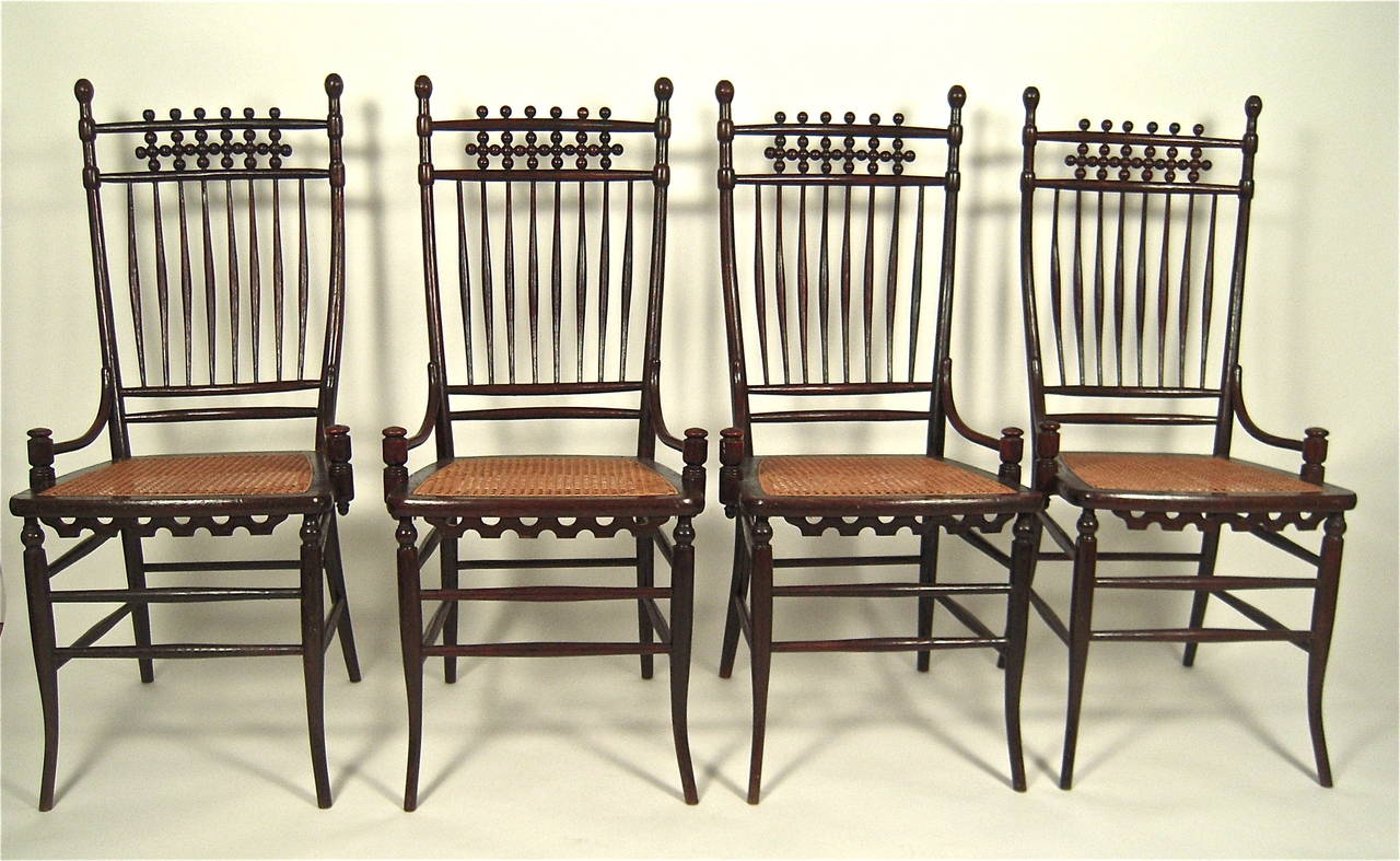 An unusual set of four American Aesthetic Movement turned dark stained brown bentwood and caned chairs, late 19th century, the cresting with spheres in geometric patterns over eight spindles, each with a caned seat with shaped and pierced apron,