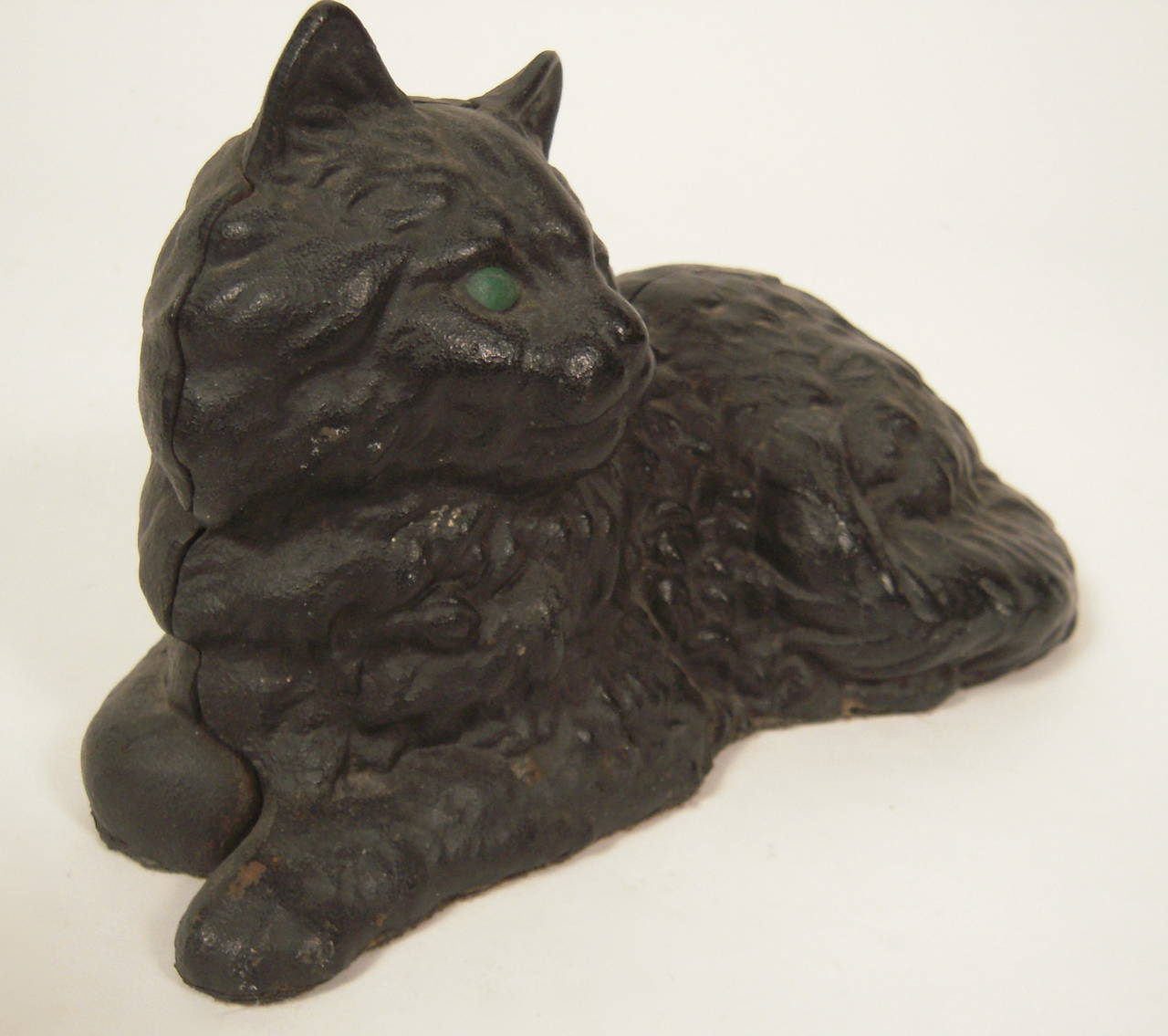 A painted cast iron doorstop of a reclining cat, black with green eyes, in original surface, attributed to Hubley, American, circa 1920s.