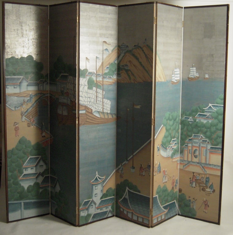 A large six-panel Chinese hand painted screen, depicting sailing ships departing from a picturesque harbor town, on silver painted ground in primarily blue and green tones. Architectural as a free standing folding screen or may be mounted as a large