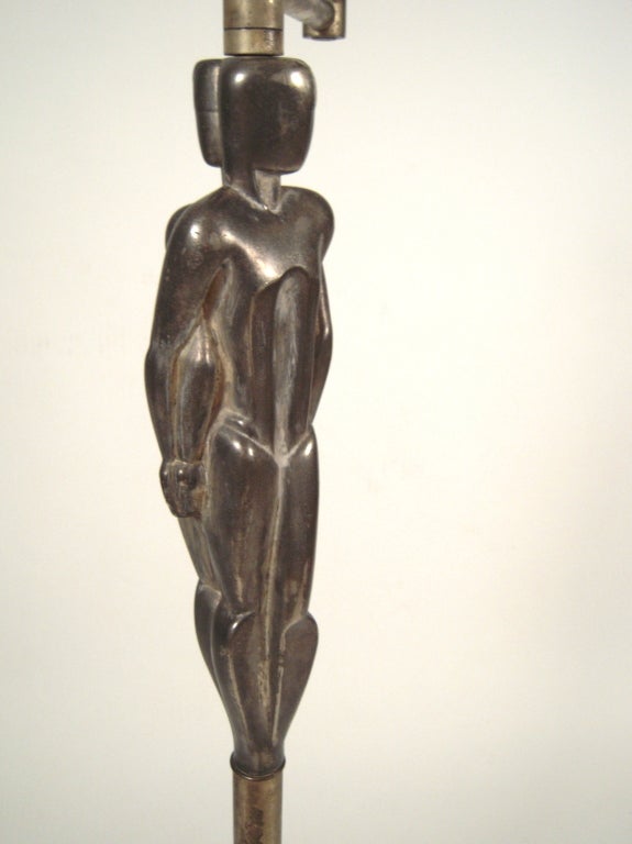 An unusual Art deco period floor lamp in silver toned metal, with adjustable swing arm, the sculptural columnar support with back to back modernist male and female figures on a cylindrical metal shaft supported by a circular stepped metal base. The