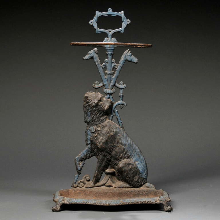 A cast iron umbrella stand with terrier, American, circa 1880,  the shaft incorporating a half-round, seated terrier cast dog with head turned and front paw raised, in front of crossed walking sticks, one with a whippet's (?) head, the other with a