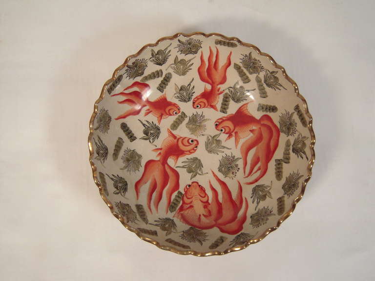 A large late 19th century Japanese pottery bowl, of circular form, with gilded bracketed edge, decorated overall with transfer printed and painted red koi fish and grey-green vegetation.