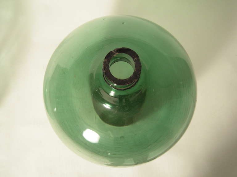 A decorative  American 19th century green blown glass demijohn bottle, with applied collar and rough pontil mark on base.

In the 19th century, when provisions were sold in bulk, demijohns were the storage vessel of choice for wine merchants.