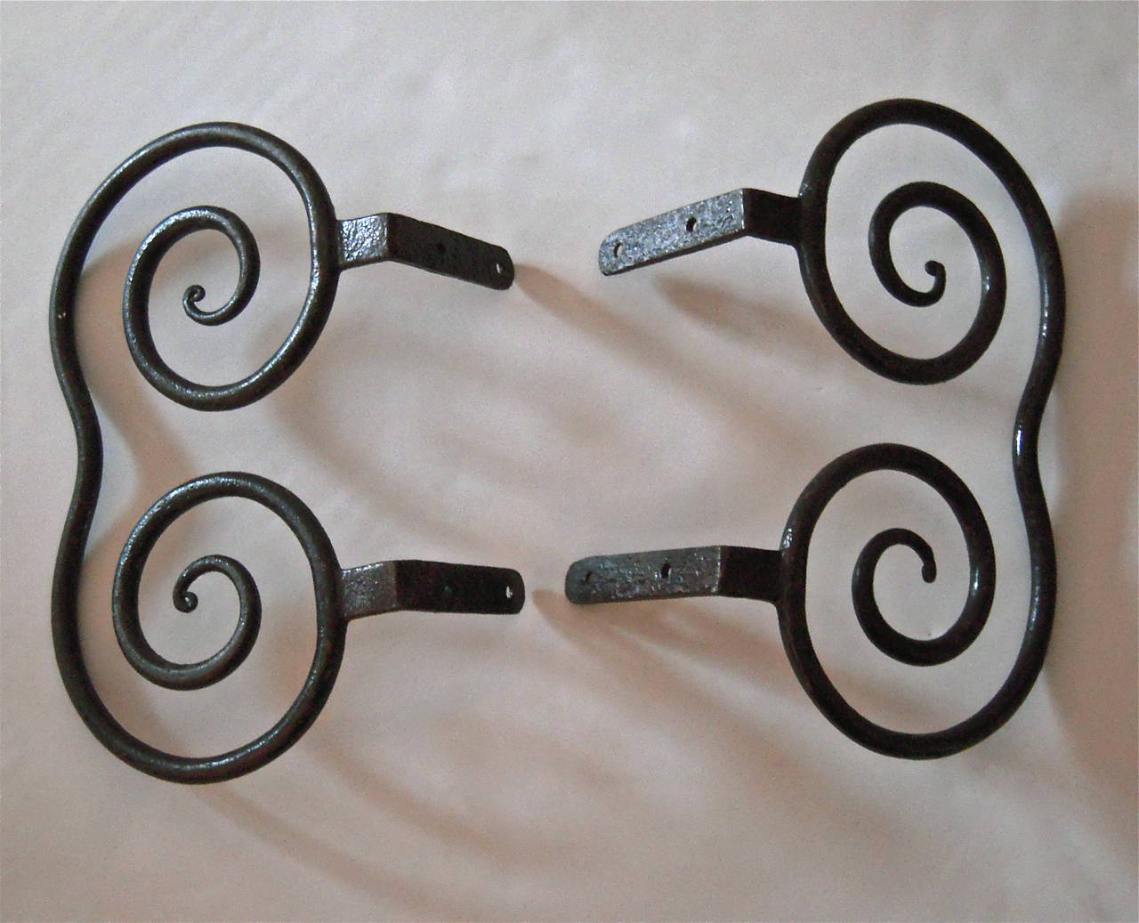A rare pair of stagecoach steps, which make for graphic and unusual decorative wall-mounted or tabletop sculptures, American, 19th century, each forged from half-inch round iron stock forming opposing curls with two 