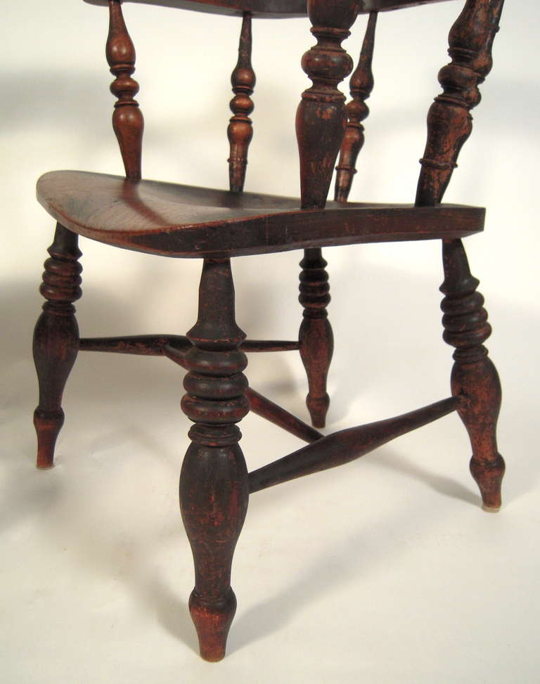 A pair of 19th century American country black painted Windsor Captain's chairs, the barrel backed and shaped arms supported by boldly turned vase and ring spindles, raised on similarly turned legs.