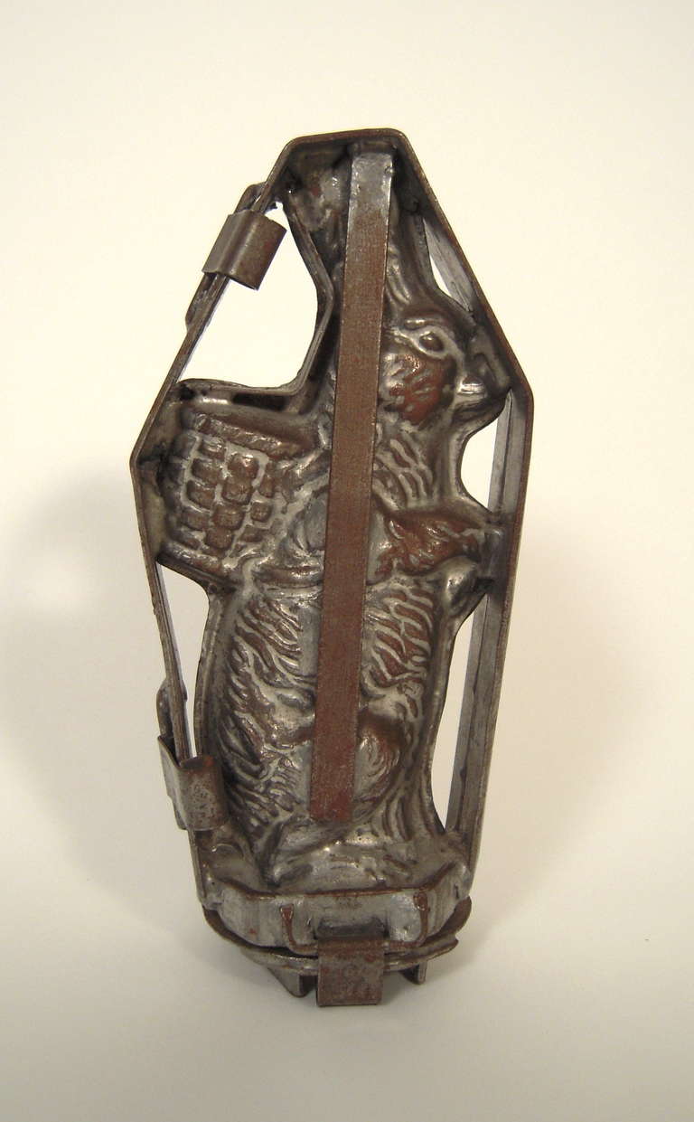 A cast aluminum two-part chocolate mold, in the form of a standing Easter bunny with a woven basket on his back.