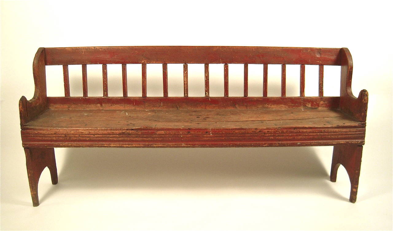 A diminutive, character-filled red painted spindle back bench with shaped and arched ends, in wonderful old surface. Structurally sound. Perfect for the end of a bed, a hallway, or landing, American, 19th century.

Dimensions: Height: 29