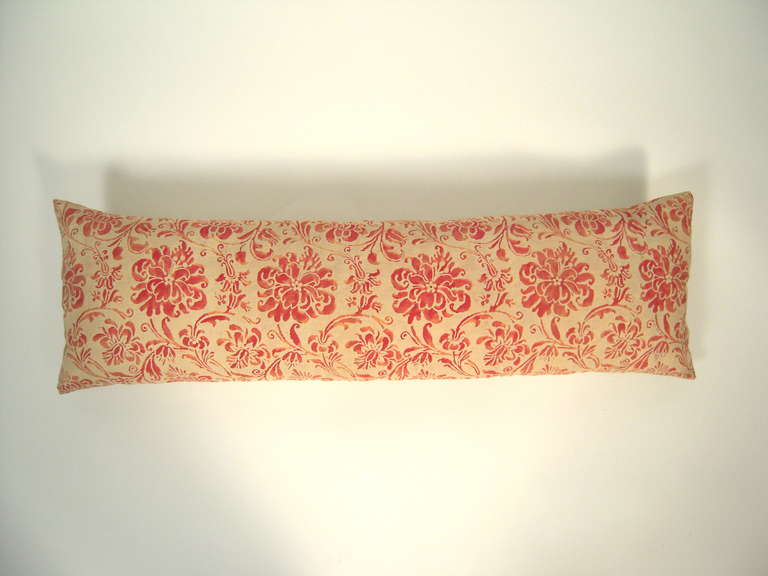 An antique red and buttery cream Fortuny fabric rectangular lumbar pillow, down filled and backed with silk, in a beautiful, variegated floral and foliate pattern.