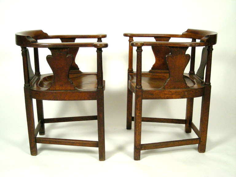 A pair of very comfortable, fine and unusual  george iii english country tavern armchairs in oak, spacious and well proportioned, with deep saddle seats, carved from the solid, the curved back and scrolled arms  supported by ring-turned columnar